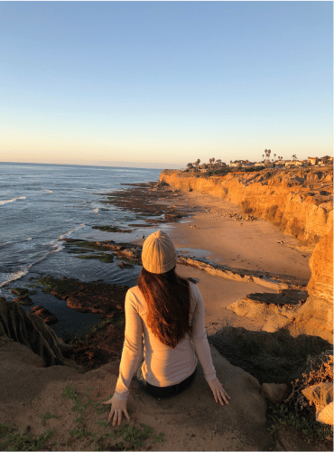 Girl sitting on the edge of a cliff at sunset cliffs san diego